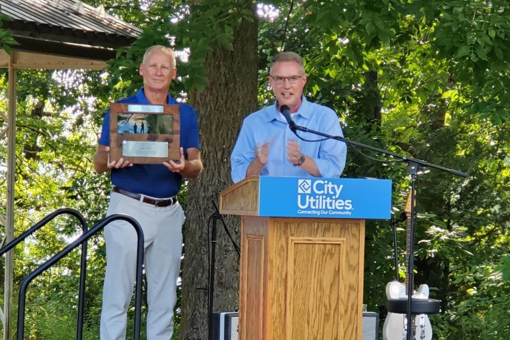 Gary Gibson, right, CU's general manager, applauds the naming of the recreational area in honor of his predecessor, Scott Miller.